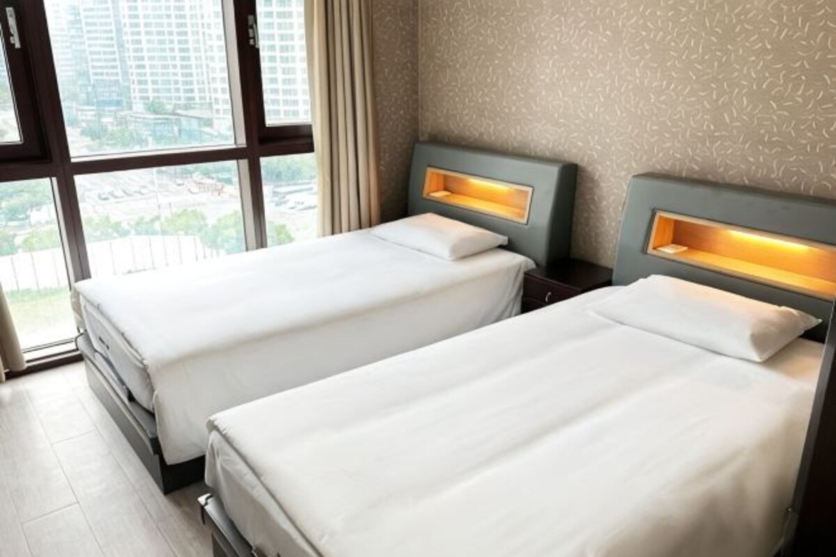 A hotel room with two beds, a window with a view, and a patterned wall.