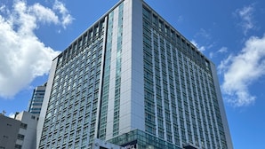 A high-rise building with a modern glass facade and a prominent corner entrance. - CENTUMCITY HOTEL (Busan)