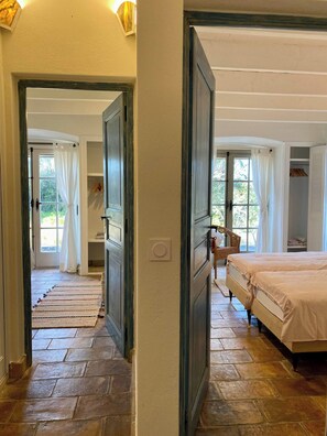 Ein Schlafzimmer mit einem Bett, einem Fenster mit Vorhängen, einem Sessel und einem Kleiderschrank.