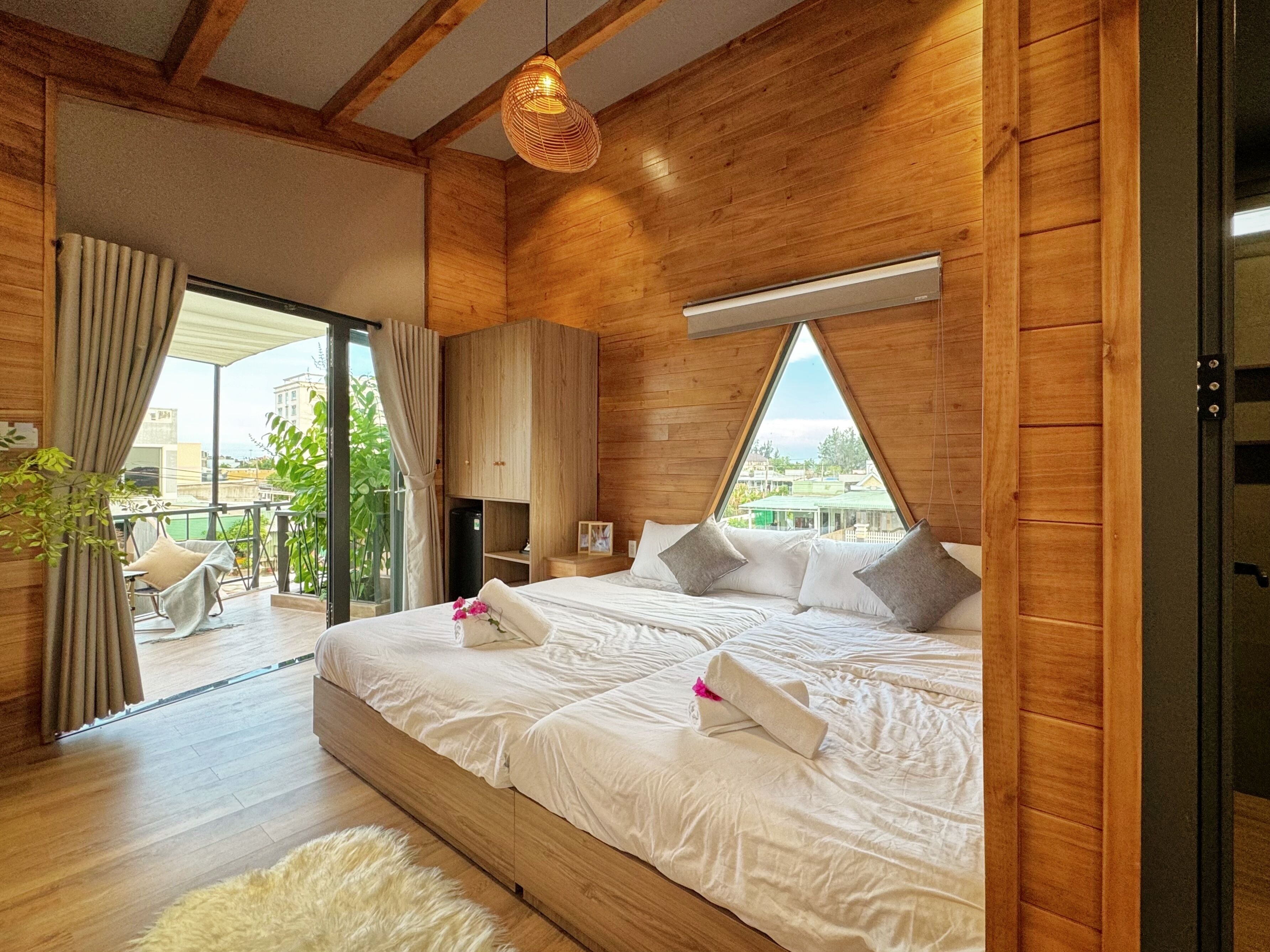 A bedroom with a large bed, wooden walls, a window, and a view of the outside.