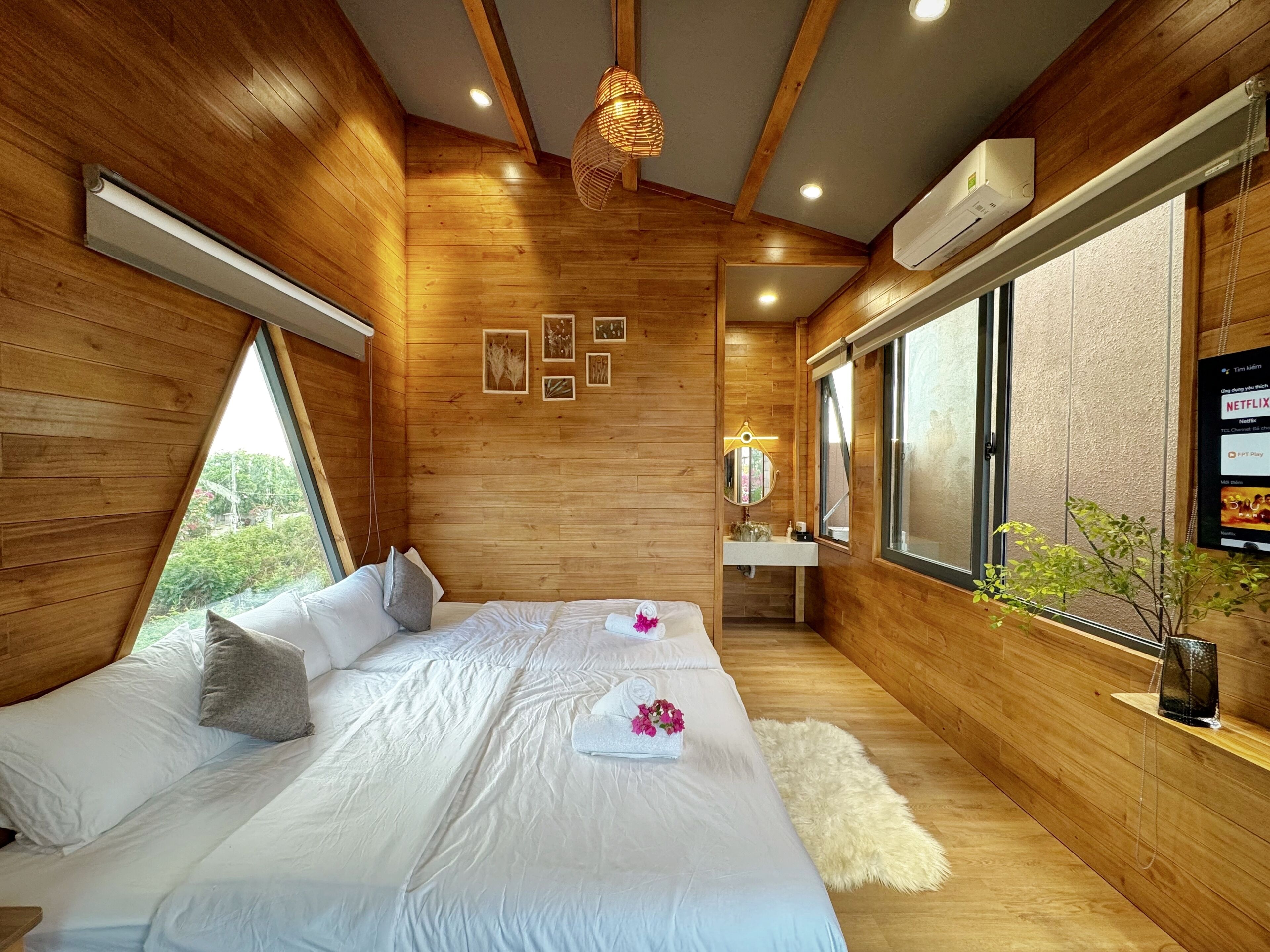 A bedroom with a wooden interior, a large bed, a window, and a wall-mounted air conditioner.
