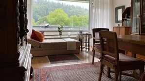 Un salon confortable avec une grande fenêtre, un canapé, une table à manger et un fauteuil.