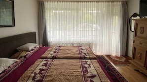 Une chambre à coucher avec un lit, une commode et une fenêtre ornée de rideaux légers.
