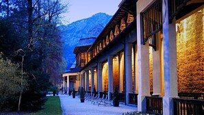 Un hôtel dont les chambres, alignées les unes à côté des autres, sont dotées de grandes fenêtres et dont la façade est en pierre.