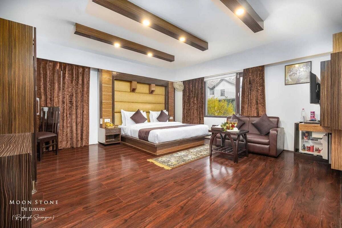 A modern hotel room with a large bed, a sofa, a small table, and a TV.