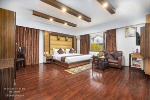 A modern hotel room with a large bed, a sofa, a small table, and a TV. - Hotel Moonstone de luxury (Srinagar)