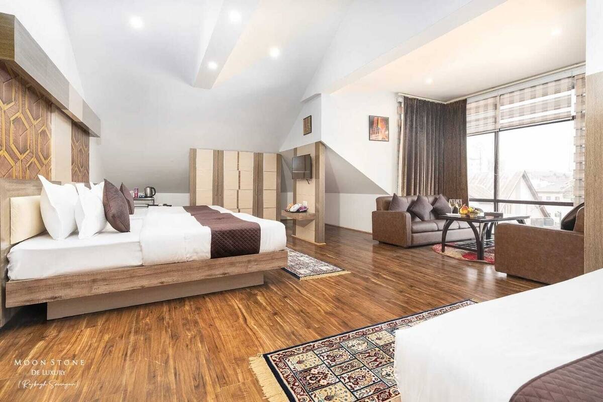 A modern hotel room with a bed, sofa, and a balcony with a view.