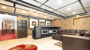 A modern lobby with a reception desk, leather seating, and a patterned rug. - Hotel Moonstone de luxury (Srinagar)
