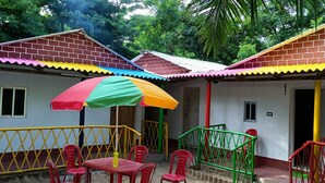 A building with colorful roofs and a small outdoor seating area with red plastic chairs and a table. - Bagda Beach Resort (Balasore)