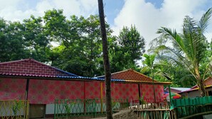 A residential area with brick houses, a green fence, and a palm tree. - Bagda Beach Resort (Balasore)