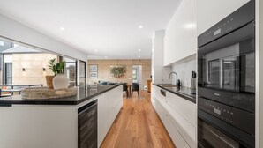 A modern kitchen with a central island, built-in appliances, and a view to the outside. - Mintaro - Point Lonsdale (Point Lonsdale)