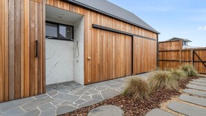 A modern building with a wooden exterior, a stone-tiled entrance, and a metal door. - Mintaro - Point Lonsdale (Point Lonsdale)