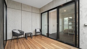 A modern, minimalist balcony with wooden flooring, two chairs, and a small table. - Mintaro - Point Lonsdale (Point Lonsdale)