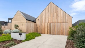A modern building with a large wooden barn-like structure, a concrete pathway, and a small utility box labeled '6'. - Mintaro - Point Lonsdale (Point Lonsdale)