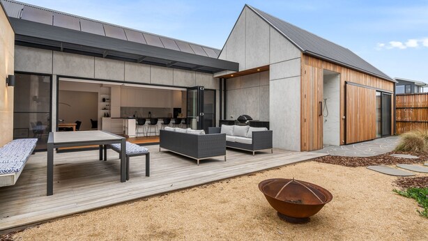 A modern house with a patio area featuring a dining table, sofas, and a fire pit. - Mintaro - Point Lonsdale (Point Lonsdale)