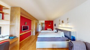 A modern hotel room with a large bed, a desk with a computer, and a TV.