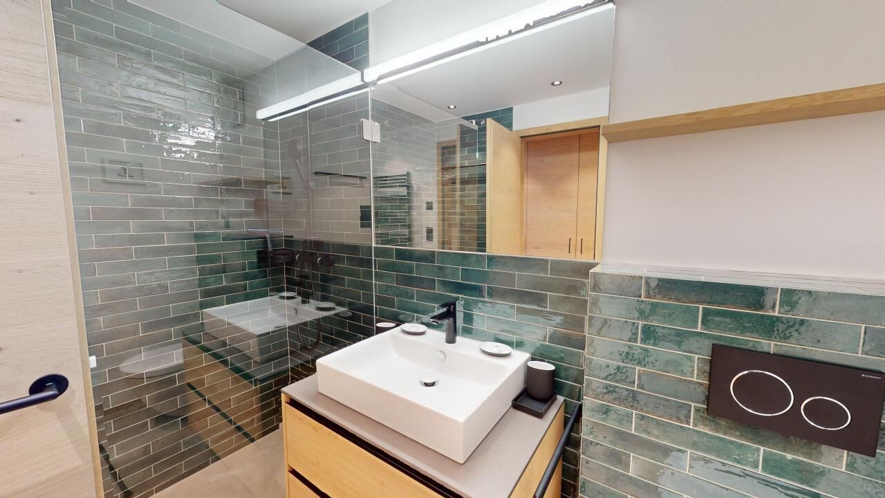 Une salle de bain moderne avec une douche à l’italienne en verre, un lavabo blanc et un meuble-lavabo en bois.