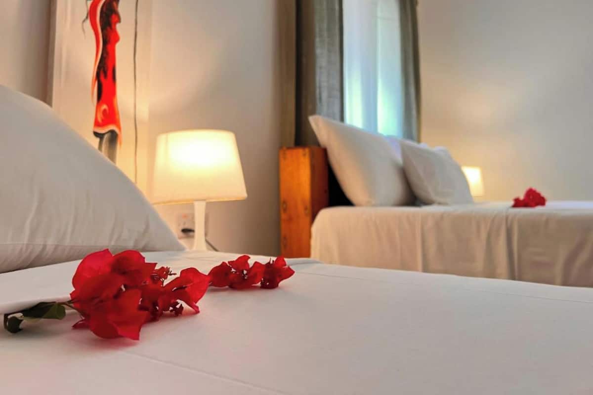 Ein Hotelzimmer mit zwei Betten, weißer Bettwäsche, einer Lampe und einem dekorativen Wandbild.
