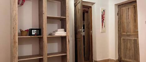 A room with a wooden wardrobe, a door, a tiled floor, and a hanging light fixture.