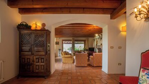 A spacious living area with a wooden cabinet, a red chair, and a tiled floor. - Tenuta Castagnera (Tarzo)