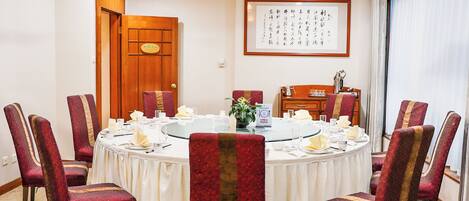 A conference room with a round table, red upholstered chairs, and a wooden cabinet with a sign.