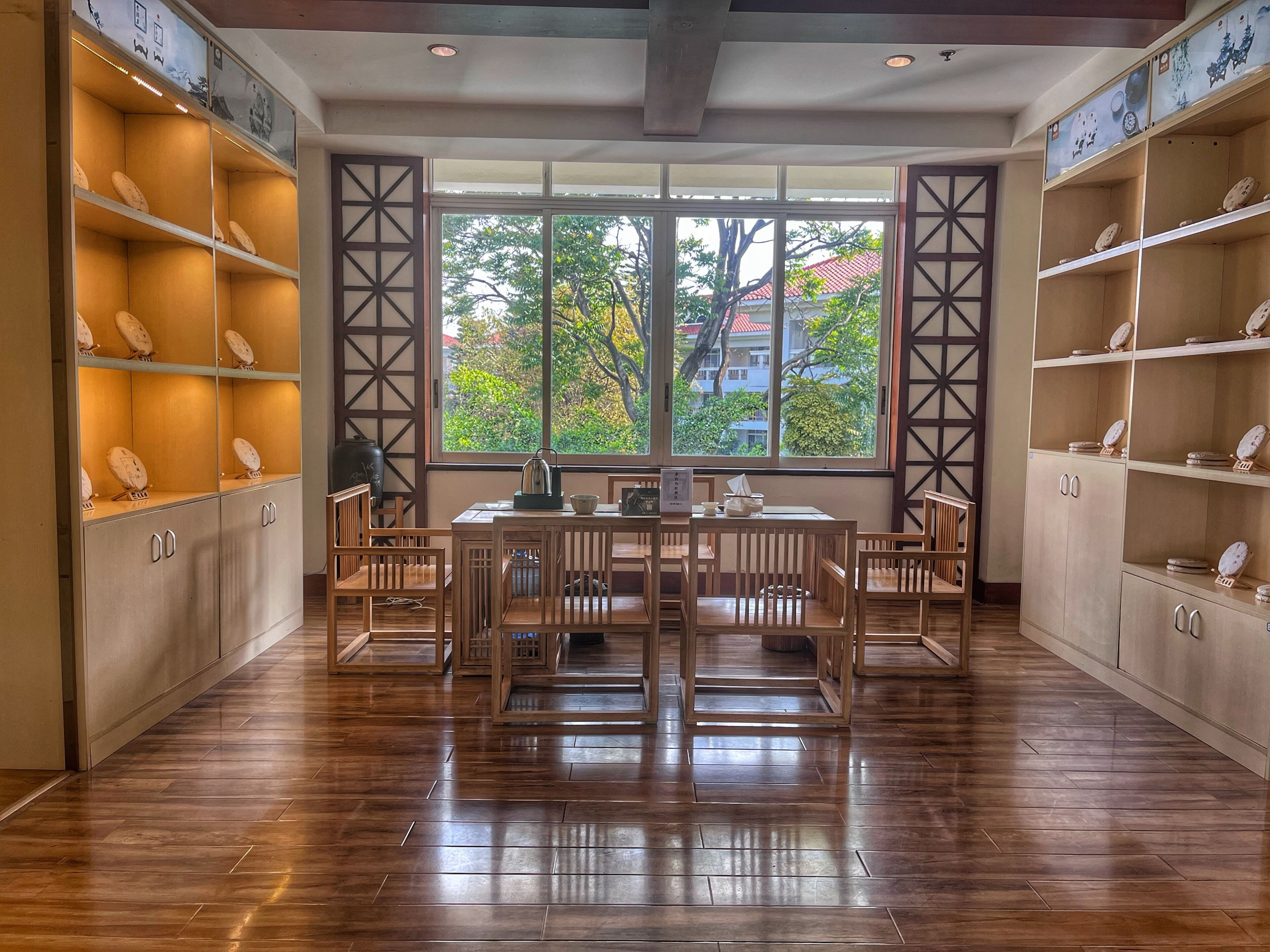 A room with a wooden floor, a table with chairs, and shelves with decorative items.