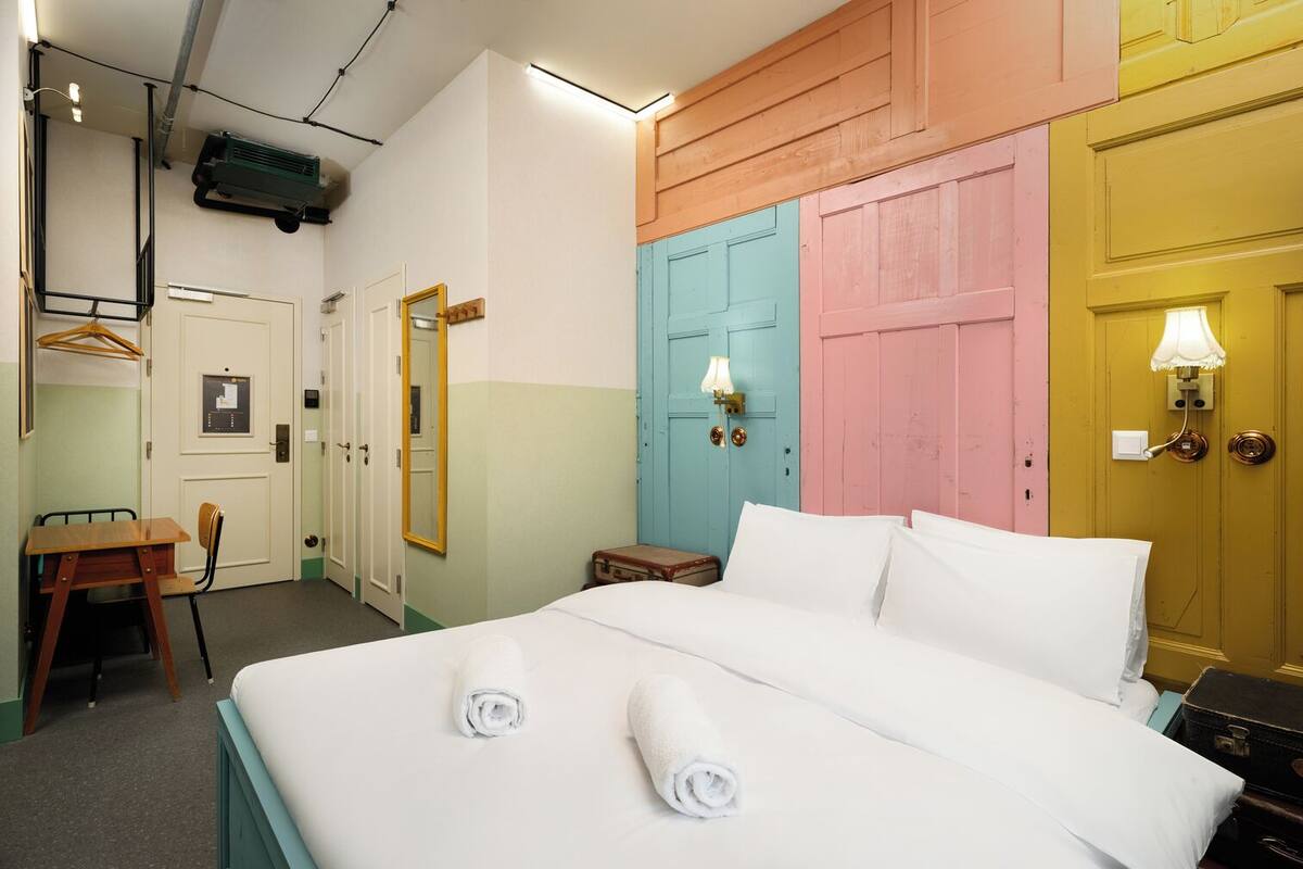 A hotel room with a bed, a desk, a chair, and a wardrobe.