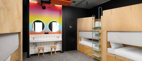 A bunk room with a bathroom, including a sink, mirror, and toilet.
