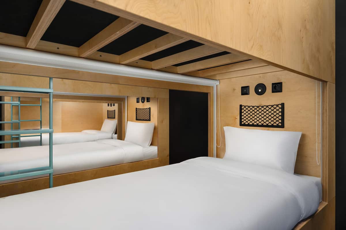 A compact room with two beds, a glass partition, and a wooden ceiling.