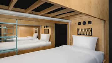 Habitación compacta con dos camas, un separador de vidrio y techo de madera.