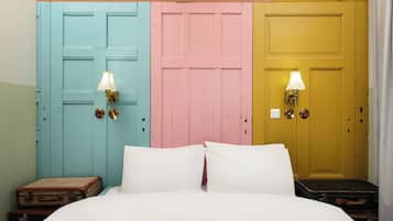 A bed with white bedding, three doors in pastel colors, and wall-mounted lamps.