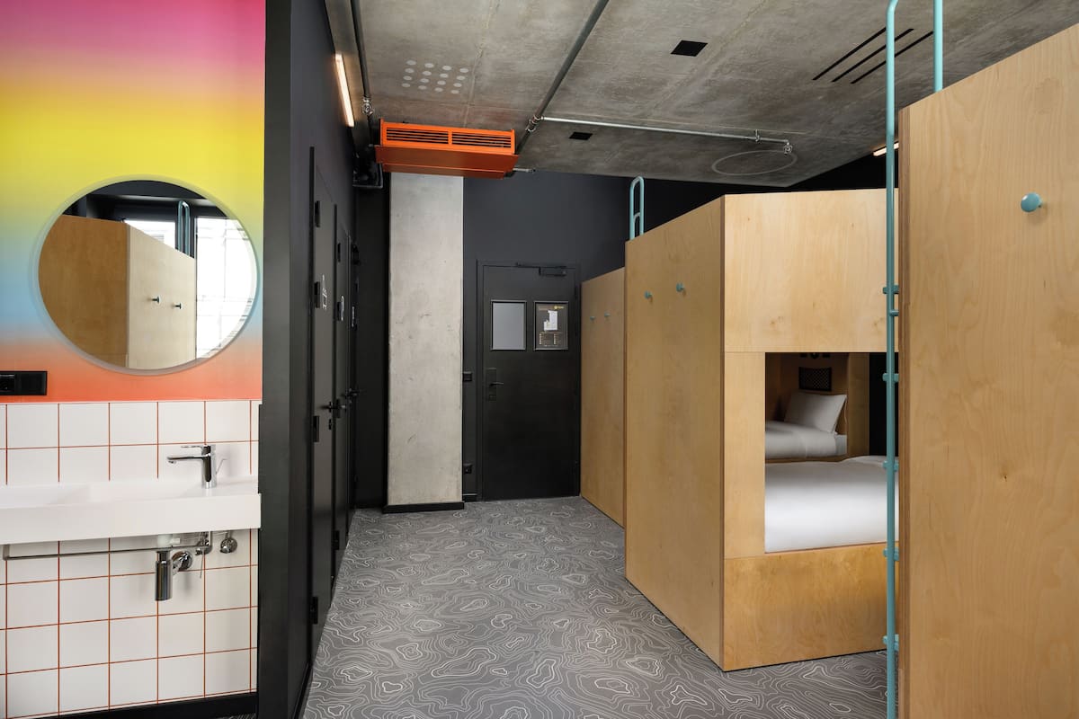 A compact room with a small bed, a sink, and a mirror.
