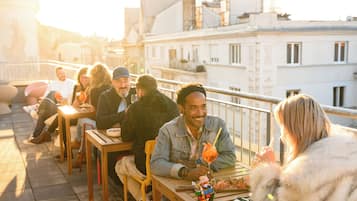 A group of people dining outdoors on a terrace with a cityscape in the background.