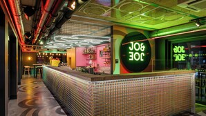 A bar area with a neon sign, a patterned floor, and a modern ceiling design. - JO&JOE Budapest (Budapest)