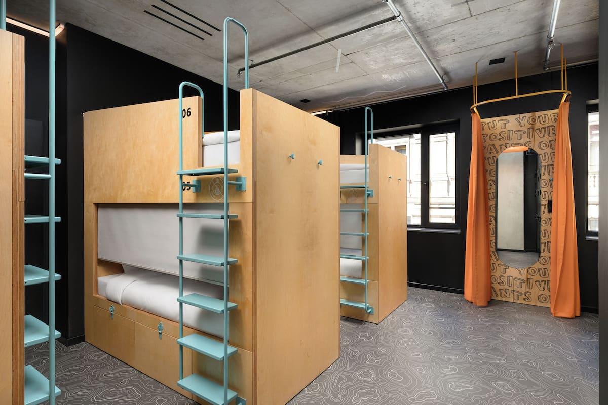 Bunk beds with metal ladders, a patterned floor, and a window with curtains.