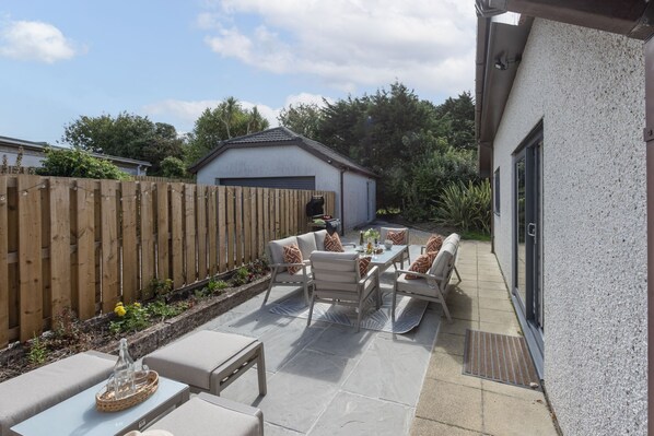 A patio area with outdoor furniture, a barbecue grill, and a small shed.