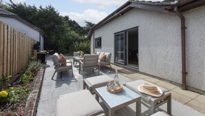 A patio with outdoor furniture, a wooden fence, and a house with a large sliding glass door. - Tre Lowen- Enclosed Garden - Free Parking (Perranporth)