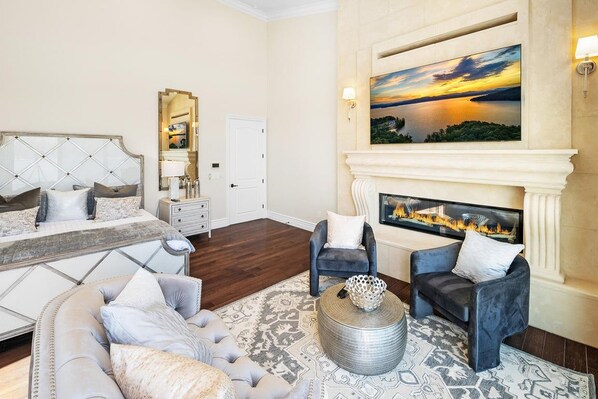 Un dormitorio con una cama grande, una chimenea y vistas a un atardecer.