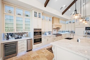 A spacious kitchen with white cabinetry, a large island, and a built-in oven.