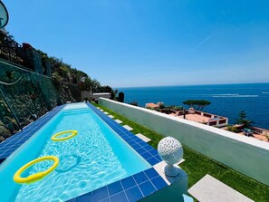 A swimming pool with a view of the sea, a white spherical light fixture, and a stone wall. - Luxury Villa - La Balena Blu with Pool and Sea View (Massa Lubrense)