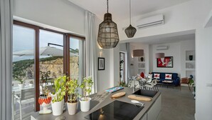 Eine moderne Küche mit einer zentralen Kochinsel, großen Fenstern und Blick ins Freie.