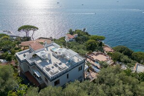 Une propriété située en bord de mer, dotée d’une terrasse sur le toit, d’une piscine et offrant une vue sur l’océan.