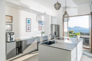 Una cocina moderna con una isla central, electrodomésticos de acero inoxidable y vistas al mar.