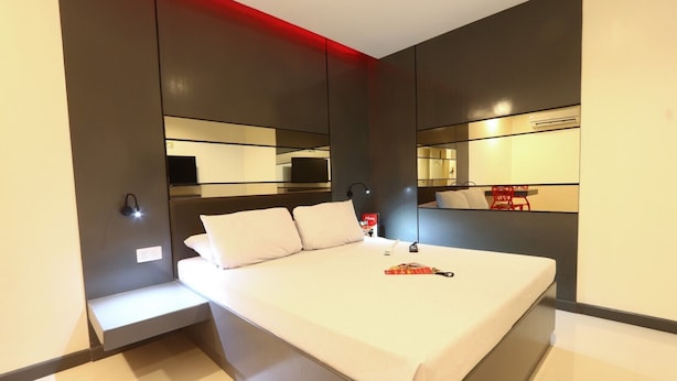 Ein modernes Hotelzimmer mit einem großen Bett, Nachttischen, einem Spiegel und einer roten Akzentwand.