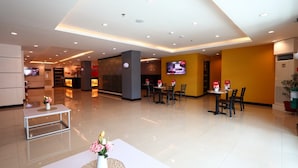 Eine Hotelhalle mit einer Rezeption, einer Sitzecke und einem Fernseher.