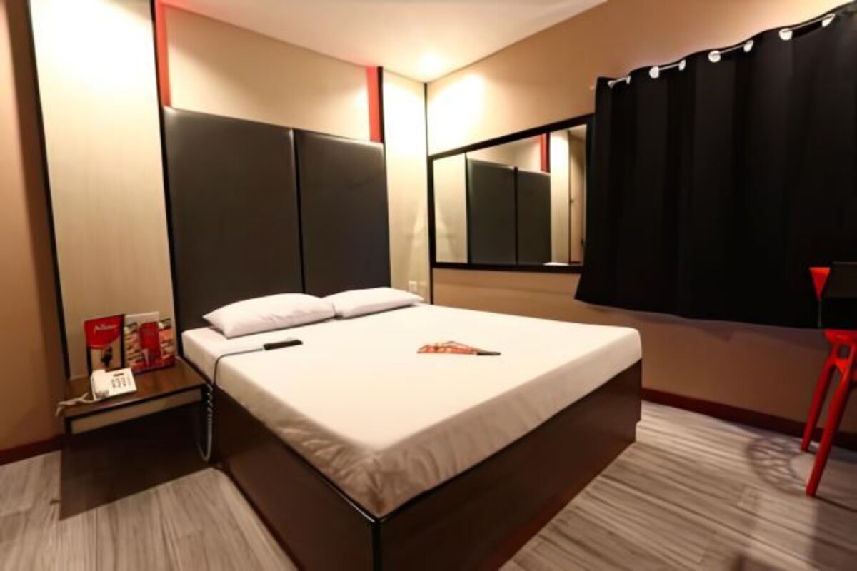 Een hotelkamer met een bed, nachtkastje en een spiegel.