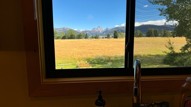 A window with a view of a field and mountains.