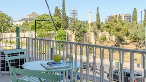 Ein Balkon mit Tisch, Stühlen und Blick auf eine Stadtlandschaft mit Gebäuden und Bäumen.