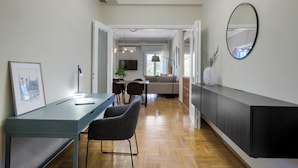 Eine moderne Küche mit einer langen Arbeitsplatte, zwei Barhocker und einem Essbereich mit Tisch und Stühlen.