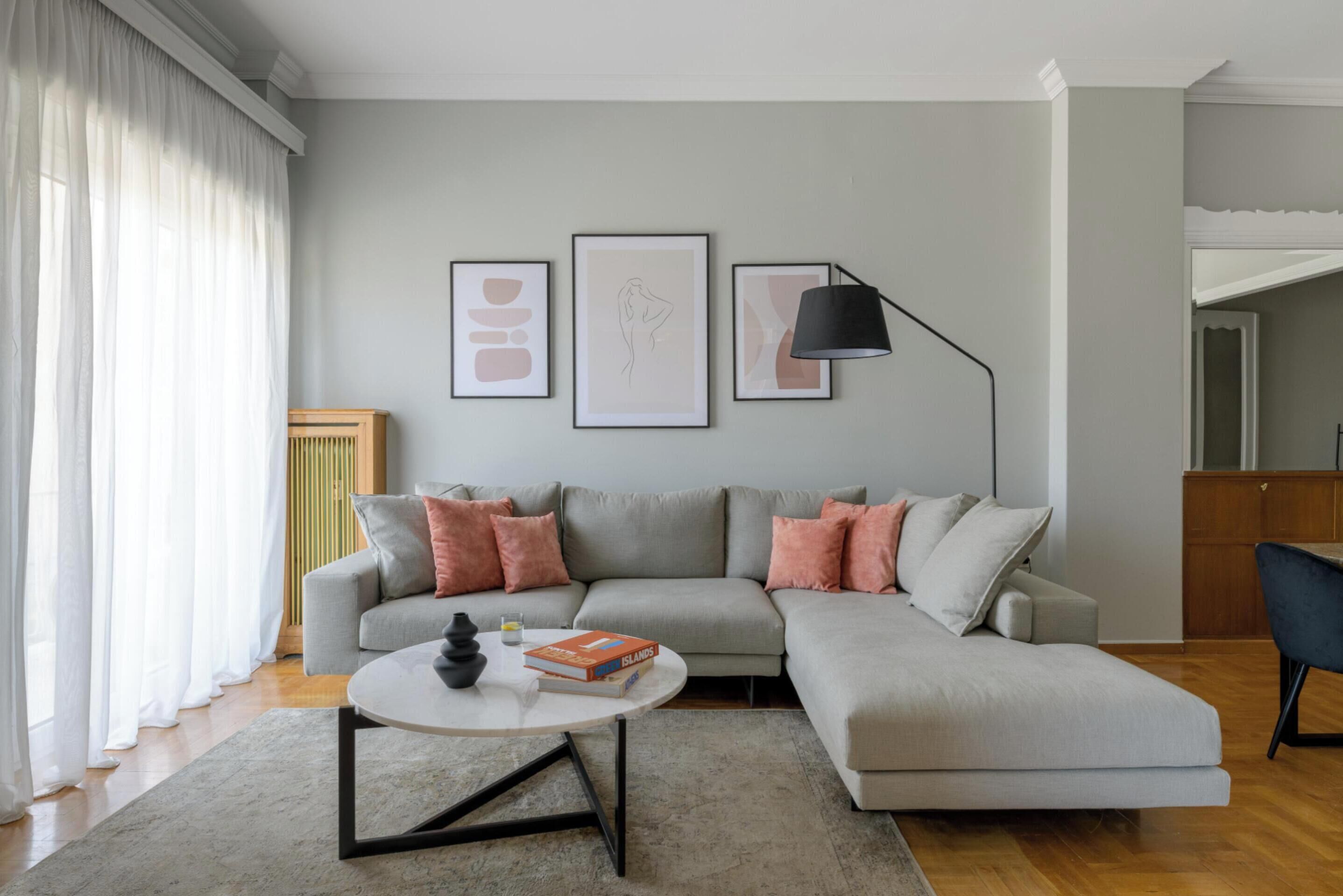 A modern living room with a grey sectional sofa, a round coffee table, and framed artwork on the wall.